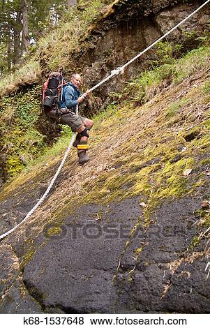 a hiker uses a rope to climb up a steep slope on Nootka Island, BC, Canada View Large Photo Image Stock Photo - a hiker uses a rope to climb up a steep slope on Nootka Island, BC, Canada. Fotosearch