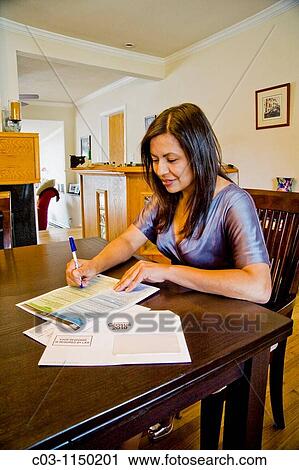 Stock Image - A Hispanic woman fills out her 2010 U S Census form at home in California Administered every ten years, the census is an important tool of efficient government. Fotosearch