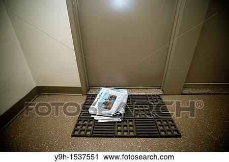 Stock Image - A home delivery copy of the New York Times, containing some of the Sunday sections, is seen in front of a door in an apartment building in New York on Saturday, September 17, 2011? Richard B Levine. Fotosearch