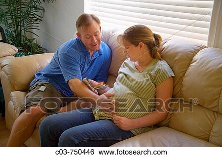 A husband affectionately pats the belly of his nine-month-pregnant wife at home while reading to her in Lake Forest, CA, USA (note baby furniture in foreground) View Large Photo Image Stock Photograph - A husband affectionately pats the belly of his nine-month-pregnant wife at home while reading to her in Lake Forest, CA, USA (note baby furniture in foreground). Fotosearch