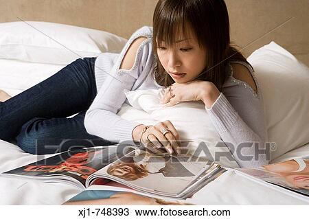 A Japanese woman resting on her hotel room bed reading a magazine View Large Photo Image Stock Image - A Japanese woman resting on her hotel room bed reading a magazine. Fotosearch