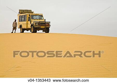 Stock Image - A landrover and a man in the desert of the Skeleton Coast Park, Namibia, Africa. Fotosearch