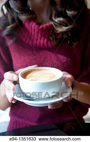 Stock Image - A large coffee cup being held in a woman's hands.. Fotosearch