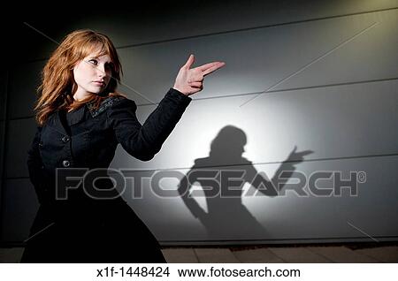 A late teen early 20s single woman girl with red hair pointing her fingers like a gun, casting shadow, UK View Large Photo Image Picture - A late teen early 20s single woman girl with red hair pointing her fingers like a gun, casting shadow, UK. Fotosearch