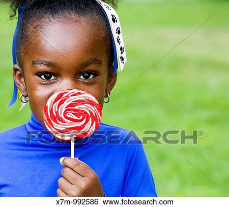 Stock Photograph - A little black girl and her swirly lollipop. Fotosearch