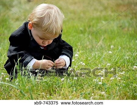 Stock Photography - A little boy squatting in the grass. Fotosearch