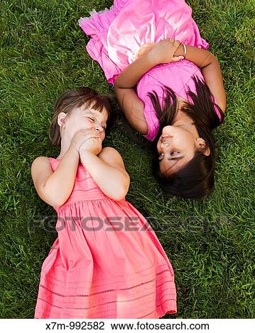 A little caucasian girl and an Asian Indian girl lay in the grass to relax and play View Large Photo Image Stock Image - A little caucasian girl and an Asian Indian girl lay in the grass to relax and play. Fotosearch