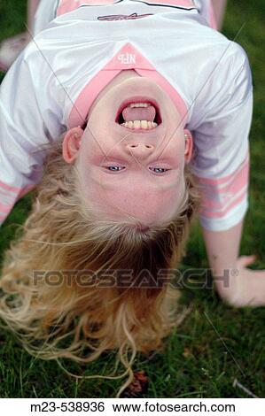 Stock Photograph - A little girl smiles while upside-down. Fotosearch