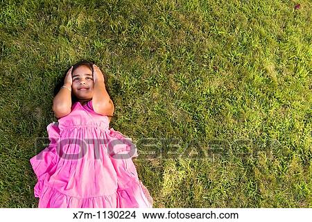 A little Indian girl thinking while laying on green grass View Large Photo Image Picture - A little Indian girl thinking while laying on green grass. Fotosearch