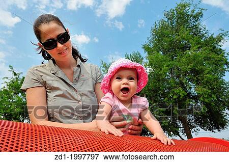 A little six month old baby girl plays with her mom in a playground. View Large Photo Image Stock Photo - A little six month old baby girl plays with her mom in a playground.. Fotosearch