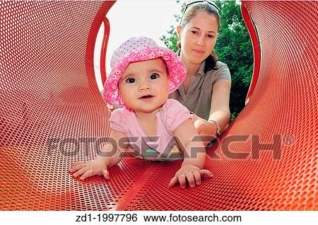 A little six month old baby girl plays with her mom in a playground. View Large Photo Image Stock Photograph - A little six month old baby girl plays with her mom in a playground.. Fotosearch