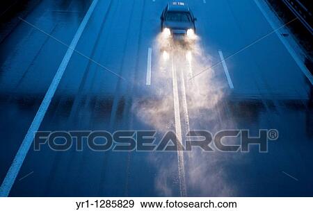 Stock Photo - A lonely car on the german Autobahn during heavy rain at dusk.. Fotosearch