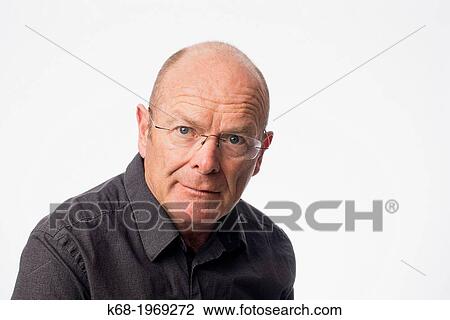 Stock Image - A man, 61, in a head and shoulders portrait in a studio. Fotosearch