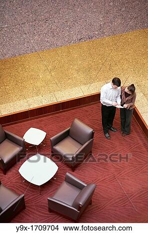 A man and a woman discuss paperwork and reports in the lobby View Large Photo Image Picture - A man and a woman discuss paperwork and reports in the lobby. Fotosearch