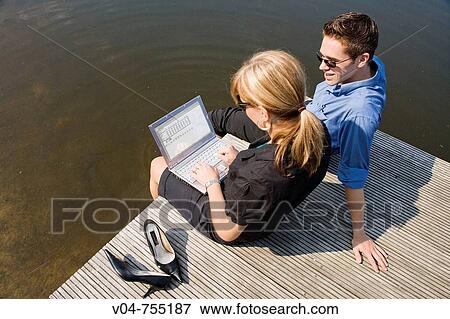 A man and a woman working on a laptop computer at a pond View Large Photo Image Stock Photo - A man and a woman working on a laptop computer at a pond. Fotosearch