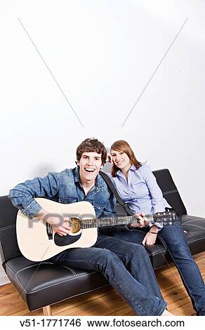 A man and woman having fun on the couch together while he plays guitar View Large Photo Image Stock Photograph - A man and woman having fun on the couch together while he plays guitar. Fotosearch
