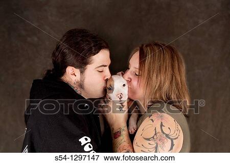 A man and woman kiss their nine-week-old Pitbull puppy in front of a blank background View Large Photo Image Stock Photo - A man and woman kiss their nine-week-old Pitbull puppy in front of a blank background. Fotosearch