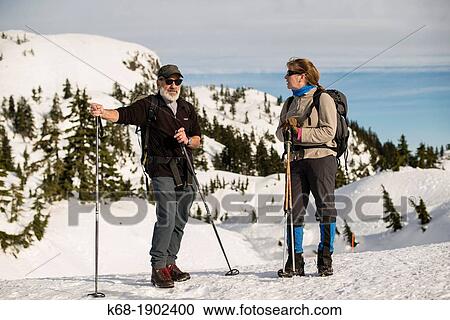 Stock Image - A man and woman pause during a winter hike on Mt Seymour, North Vancouver, BC, Canada. Fotosearch