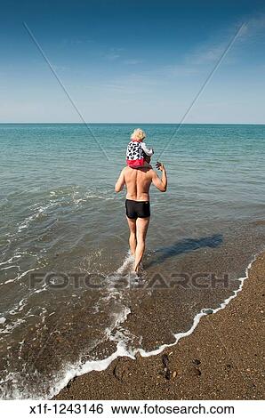 A man carrying his child on shoulders paddling in the sea Aberystwyth wales UK View Large Photo Image Stock Photograph - A man carrying his child on shoulders paddling in the sea Aberystwyth wales UK. Fotosearch