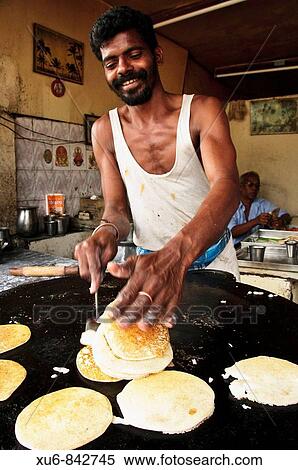 Stock Photography - A man cooking traditional Dosas at a restaurant in Kanyakumari Cape Comorin, Tamil Nadu, India. Fotosearch