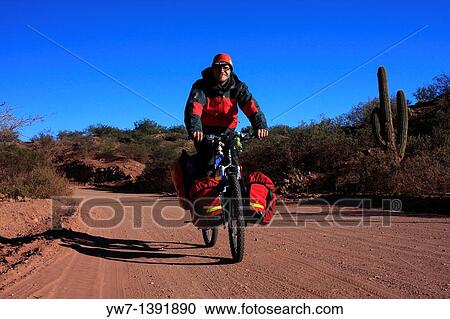 Stock Image - A man cycling on an unpaved road in Argentina, San Juan province. Fotosearch