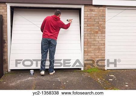 A man doing DIY painting a garage door in the Uk View Large Photo Image Stock Photo - A man doing DIY painting a garage door in the Uk. Fotosearch