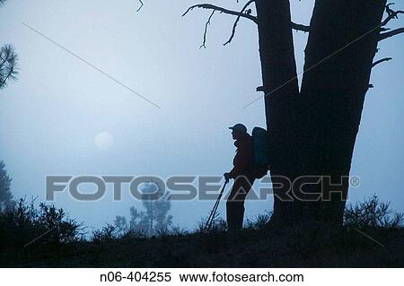Stock Photography - A man hiking at night with the full moon.. Fotosearch
