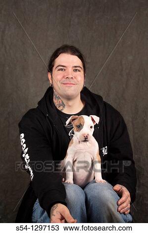 Stock Image - A man holds his nine-week-old Pitbull puppy. Fotosearch