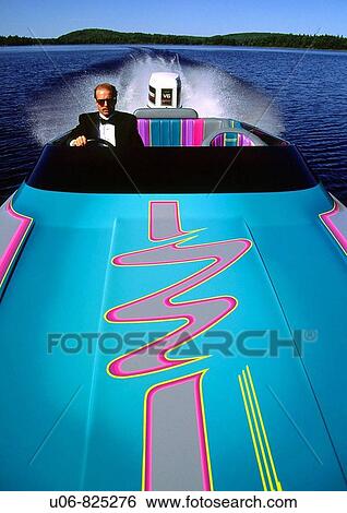 Stock Photograph - a man in a tuxedo driving a high performance powerboat on a lake. Fotosearch