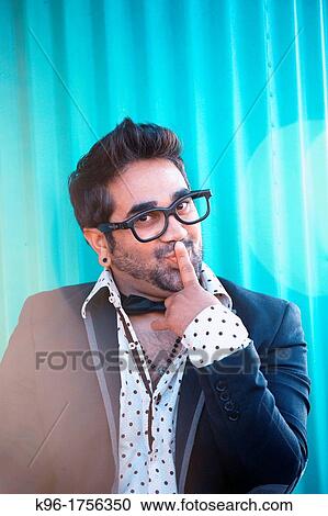 A man in suit jacket looking at the camera in a comical way with a finger over his lips View Large Photo Image Stock Image - A man in suit jacket looking at the camera in a comical way with a finger over his lips. Fotosearch