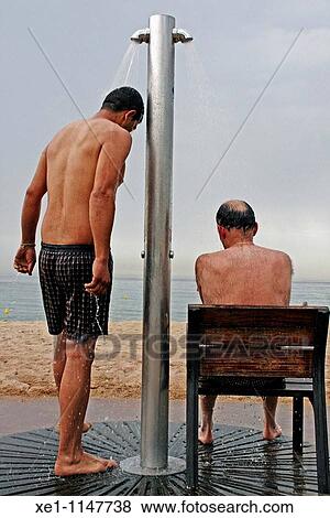 Stock Photo - A man in the shower and a man on the chair, beach, Badalona, Catalonia, Spain.. Fotosearch