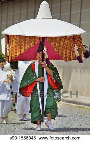 Stock Photography - A man in traditional costume carrying a large umbrella in the Aoi Maturi, in Kyoto.. Fotosearch