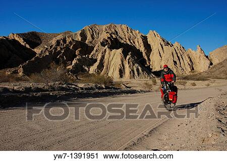 Stock Image - A man is cycling in Argentina, Salta province, north of Cafayate, in Calchaqui valley. Fotosearch