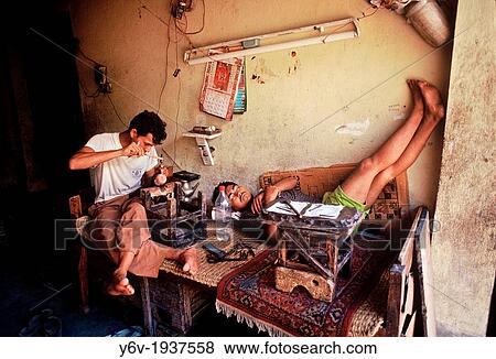 A man is working in a buddhist ritual objects workshop while another is sleeping in the workplace. Boudha, Kathmandu valley, Nepal. View Large Photo Image Stock Photo - A man is working in a buddhist ritual objects workshop while another is sleeping in the workplace. Boudha, Kathmandu valley, Nepal.. Fotosearch