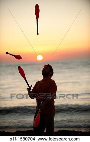 A man juggling at sunset on the beach on a very warm late september evening Aberystwyth Wales UK View Large Photo Image Picture - A man juggling at sunset on the beach on a very warm late september evening Aberystwyth Wales UK. Fotosearch