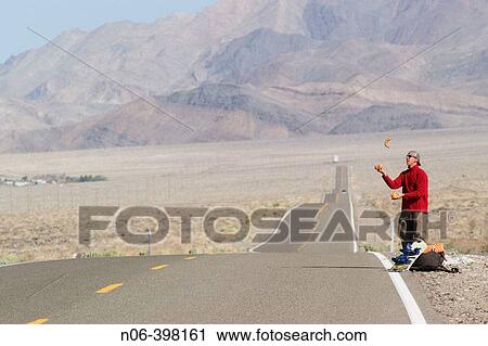 A man juggling while hitch hiking in the desert road near Lone Pine, California. USA View Large Photo Image Stock Image - A man juggling while hitch hiking in the desert road near Lone Pine, California. USA. Fotosearch