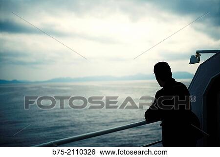 A man leaning on the railing of a boat at looking at the sea. Croosing the Mediterranean Sea from Ciutadella, Menorca to Alcudia, Mallorca, Balearic Islands, Spain View Large Photo Image Stock Photograph - A man leaning on the railing of a boat at looking at the sea. Croosing the Mediterranean Sea from Ciutadella, Menorca to Alcudia, Mallorca, Balearic Islands, Spain. Fotosearch
