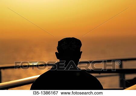 Stock Photo - A man looks at hazy sunset over the Mediterranean. Fotosearch