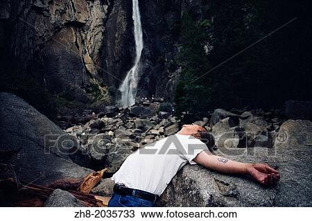 A man lying on his back with his arms spread under the foot of Bridevail Falls at Yosemite National Park in California, USA. View Large Photo Image Stock Image - A man lying on his back with his arms spread under the foot of Bridevail Falls at Yosemite National Park in California, USA.. Fotosearch