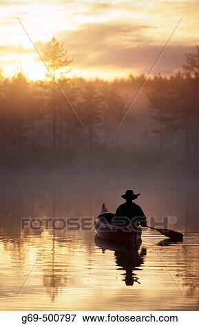 A man paddle a canoe a misty summermorning at sunrise. Byske. Vasterbotten. Sweden. View Large Photo Image Stock Photo - A man paddle a canoe a misty summermorning at sunrise. Byske. Vasterbotten. Sweden.. Fotosearch