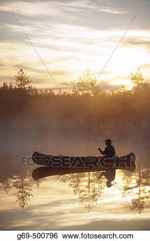 A man paddle a canoe a misty summermorning at sunrise. Byske. Vasterbotten. Sweden. View Large Photo Image Stock Photograph - A man paddle a canoe a misty summermorning at sunrise. Byske. Vasterbotten. Sweden.. Fotosearch