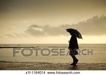 A man sheltering under an umbrella on a wet summer evening, Aberystwyth Wales UK View Large Photo Image Picture - A man sheltering under an umbrella on a wet summer evening, Aberystwyth Wales UK. Fotosearch