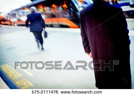 A man standing and another one walking towards the train on the platform of the York train station. Yorkshire, England, UK, Europe. View Large Photo Image Stock Photograph - A man standing and another one walking towards the train on the platform of the York train station. Yorkshire, England, UK, Europe.. Fotosearch