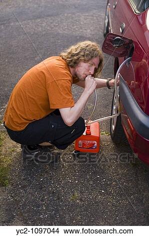 A man syphoning petrol from a cars petrol tank in the uk View Large Photo Image Picture - A man syphoning petrol from a cars petrol tank in the uk. Fotosearch