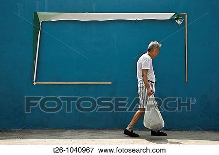 Stock Photo - A man walks down the street in front of a billboard. Shanghai, China. Fotosearch