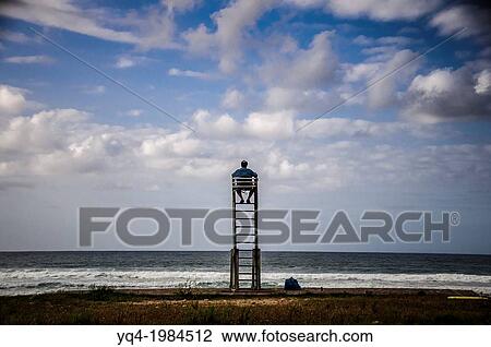 A man watches the skyline from a lifeguard chair, Caravia, Asturias. View Large Photo Image Stock Image - A man watches the skyline from a lifeguard chair, Caravia, Asturias.. Fotosearch
