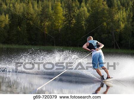 Stock Photo - A man waterskiing in the summereve, Klutmark, Vasterbotten, Sweden. Fotosearch