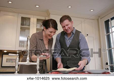 A married couple cooking and cleaning up in the kitchen of their home View Large Photo Image Stock Photography - A married couple cooking and cleaning up in the kitchen of their home. Fotosearch