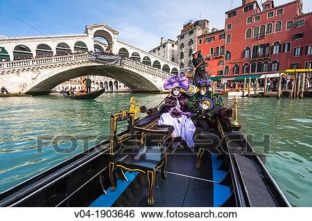 A masked couple in a gondola in front of the Rialto Bridge at the carnival in Venice, Italy, Europe View Large Photo Image Stock Photograph - A masked couple in a gondola in front of the Rialto Bridge at the carnival in Venice, Italy, Europe. Fotosearch