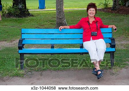 A mature woman in a red shirt sitting on a blue bench with a Canon G11 camera View Large Photo Image Stock Photo - A mature woman in a red shirt sitting on a blue bench with a Canon G11 camera. Fotosearch